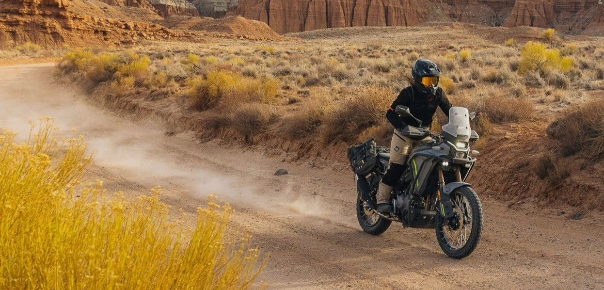Motociclista su una moto adventure in un paesaggio sterrato
